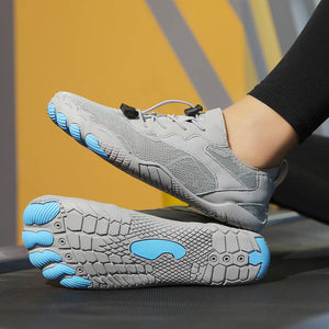 A pair of gray minimalist toe-free running shoes with bright blue accents on the toes and sole, shown with one shoe worn on a foot and the other placed flat on a treadmill.