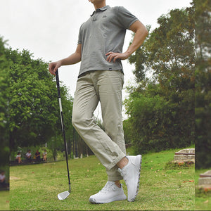 Man holding a golf club on a golf course with trees in the background