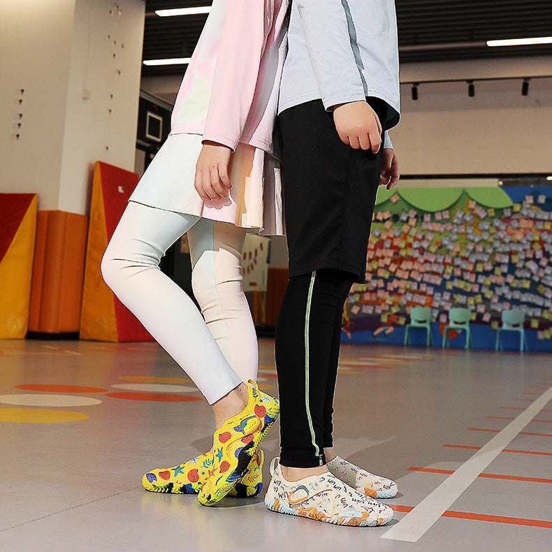 Two children standing in a gymnasium with colorful shoes.
