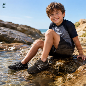 Child wearing black Tidepool Junior quick-dry water shoes on a rocky shoreline
